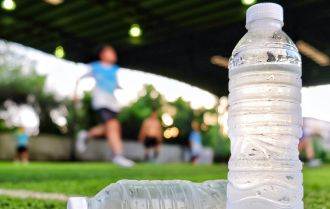 Water sport drink against soccer background on green artificial grass